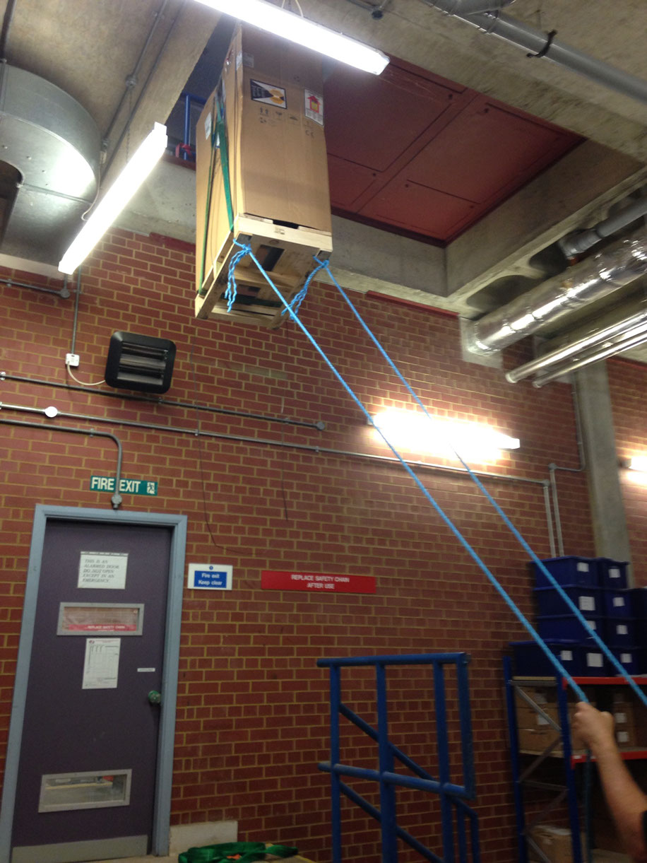 UPS (uninterruptible power supply) being hoisted up and through a small opening during installation by Enhanced Power Services Ltd.