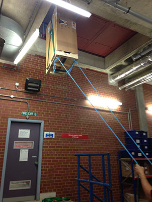 UPS (uninterruptible power supply) being hoisted up and through a small opening during installation by Enhanced Power Services Ltd.